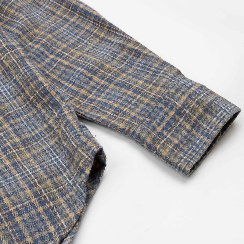 A close-up of the HARTFORD - PAUL Checked Flannel Shirt in Grey highlights the blue, brown, and grey plaid cotton fabric, with a focus on the cuff and sleeve featuring visible white buttons.