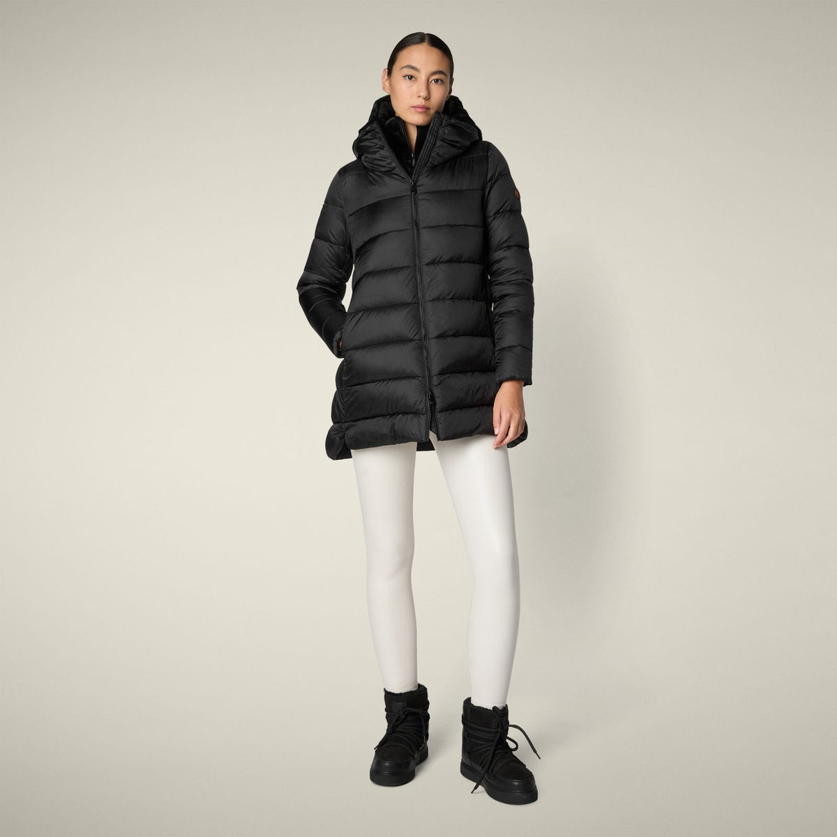 The SAVE THE DUCK - MATILDA PUFFER COAT is a black, mid-length women&#39;s jacket with a hood, horizontal quilting, front zipper, and animal-free recycled Plumtech padding, shown against a plain light background.