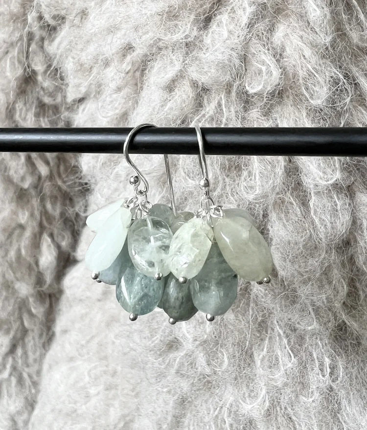 ANN LIGHTFOOT BLUE OPAL CHARM EARRINGS feature sterling silver hooks and clusters of faceted, teardrop gemstones in ombre blue, gray, and clear shades, artfully arranged like delicate petals or leaves.