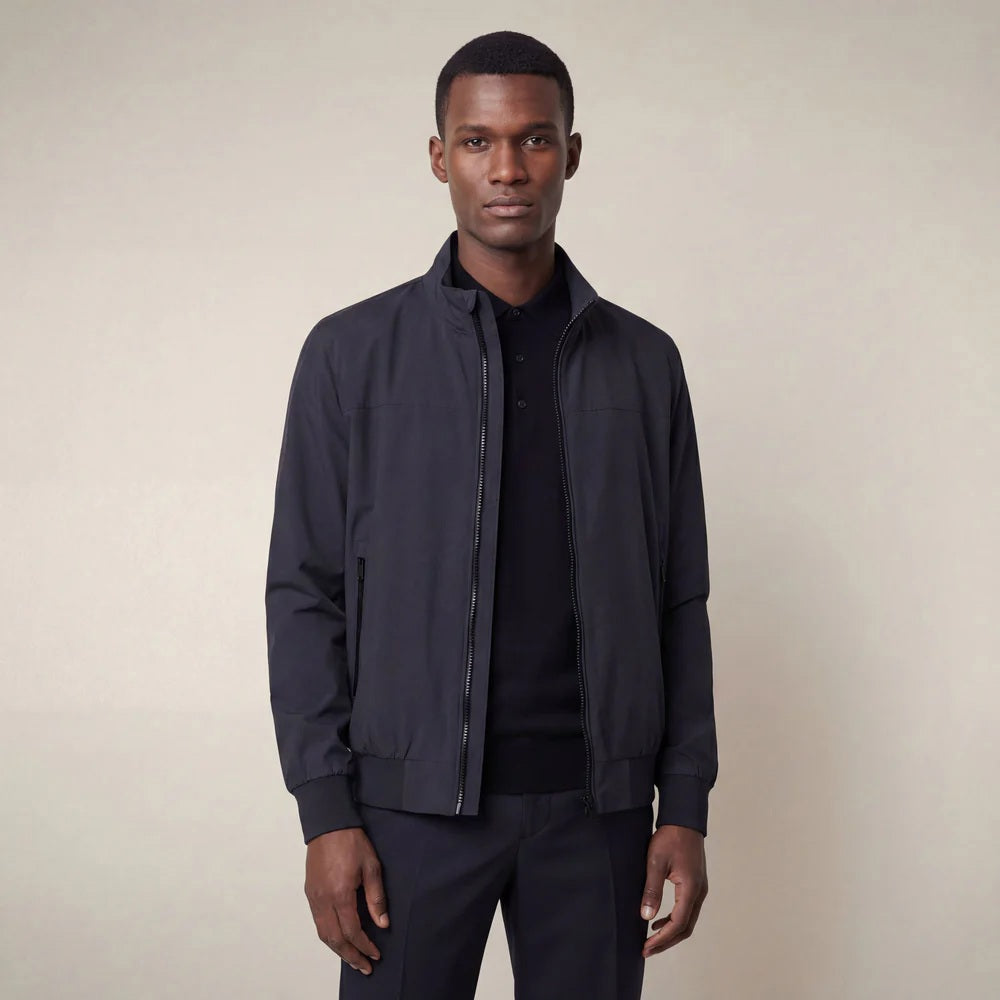 A man stands against a neutral background, wearing the SAVE THE DUCK - FINLAY JACKET IN BLUE BLACK with matching black shirt, trousers, and shoes. He has a neutral expression and his arms rest at his sides.