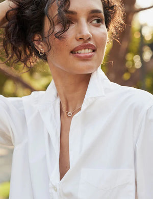 The FRANK & EILEEN Silvio Untuckable Button-Up Shirt in Superluxe Cotton, featuring a chest pocket and rolled-up sleeves, is laid flat on a textured surface. The inside label reads "Frank & Eileen EST 1947.