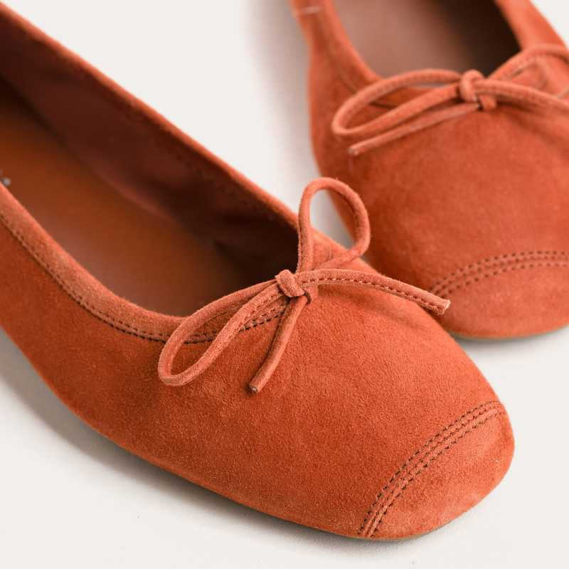 The REQINS - HARMONY Suede Ballerina Flat in Brique is shown in soft suede goatskin with a small bow on the toe, displayed side view against a plain white background.