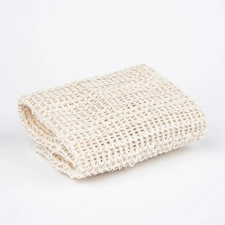 The BAUDELAIRE - SISAL WASH CLOTH by BAUDELAIRE is crafted from natural sisal fiber, harvested by hand, and features a woven texture with a brown paper label that reads “Baudelaire Sisal Wash Cloth, natural sisal fiber, harvested by hand.” This gentle exfoliator is ideal for daily cleansing or as a facial scrub, offering the benefits of natural sisal to your skincare routine.