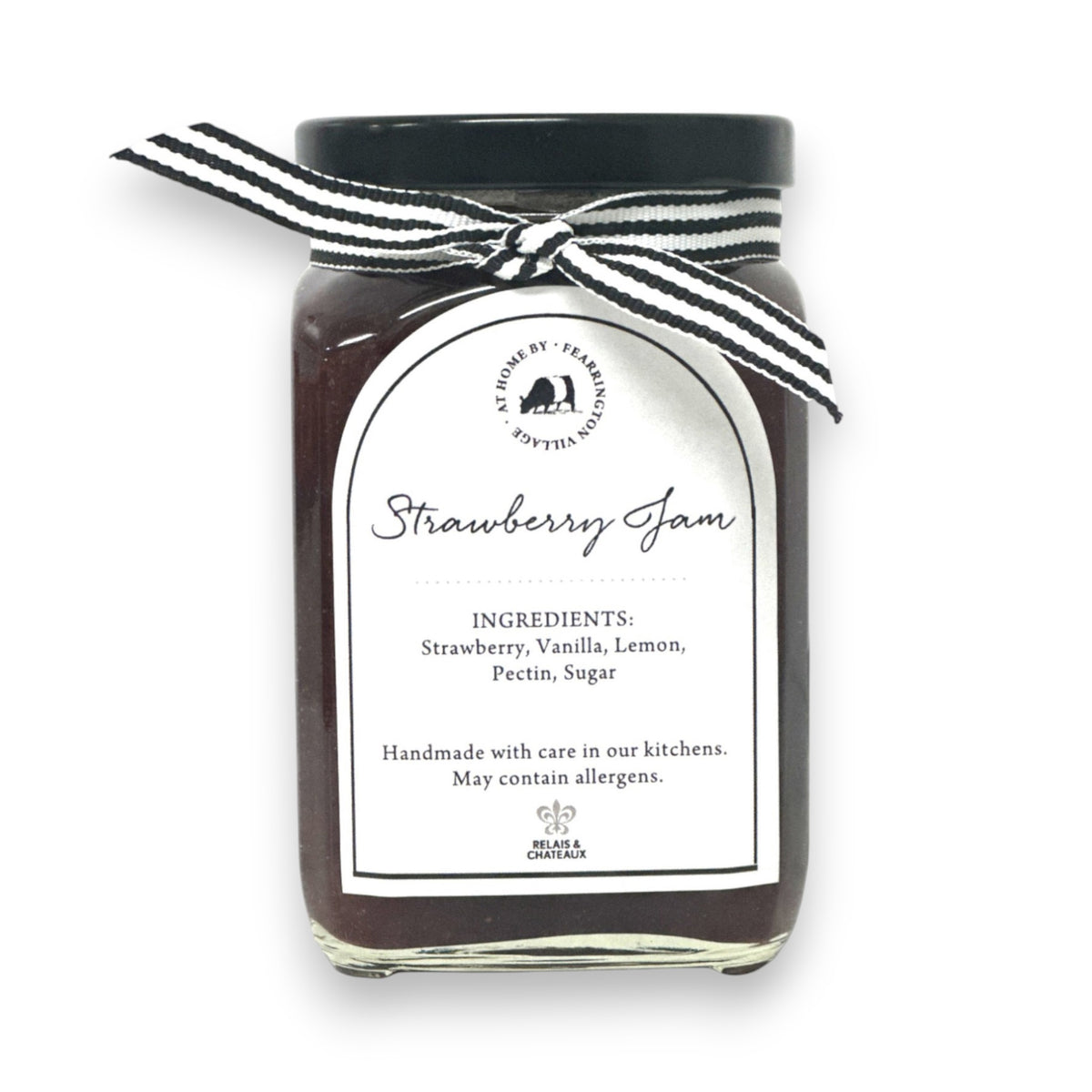 A glass jar of raspberry jam is displayed with a black and white striped ribbon adorning the lid. The white label reads &quot;Fearrington Housemade Raspberry Jam&quot; with a list of ingredients: raspberry, vanilla, lemon, pectin, sugar. The text also indicates it is handmade and may contain allergens. Perfect as a hostess gift!