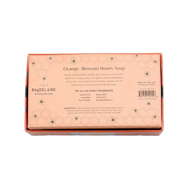 Experience the BAUDELAIRE Orange Blossom Honey Soap 3.5 oz, 2 Bar Gift Box—a beautifully presented set featuring two hexagonal orange soaps nestled in an open decorative box adorned with floral designs and a central bee illustration. This triple-milled soap by BAUDELAIRE offers a luxurious lather and a delicate orange blossom honey fragrance, making it an ideal indulgence for yourself or a thoughtful gift for someone special.