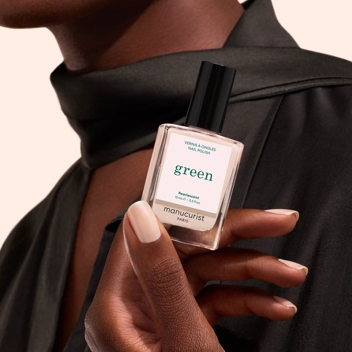A bottle of MANUCURIST INC’s GREEN™ Nail Polish in Pearlescent, featuring a quick-dry formula and intense color payoff. This vegan, non-toxic nail polish has a black cap and contains a shimmery off-white shade, delivering brilliant results without compromising on safety or performance.