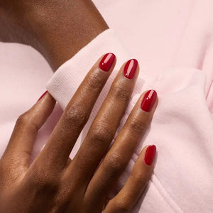 A hand with neatly manicured nails painted in MANUCURIST - GREEN™ NAIL POLISH IN DARK DAHLIA by MANUCURIST INC rests on a light pink, long-sleeve garment. The lighting highlights the glossy finish of the nail polish.