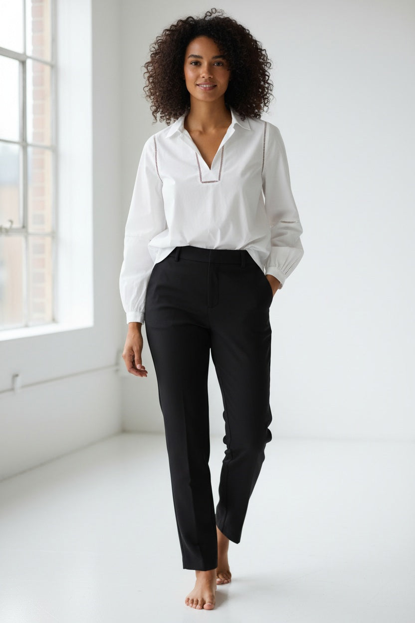 A woman with straight blonde hair wears the HINSON WU Laura Long Sleeve Lace Trim Top in White, paired with black pants, standing against a plain light background.