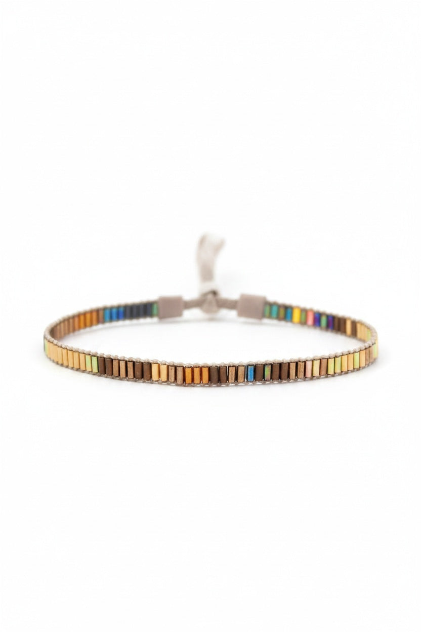 The JULIE ROFMAN - MINI BRACELET by JULIE ROFMAN JEWELRY is a vibrant handwoven piece adorned with small, square beads in various shades of pink, red, and white. It is displayed against a white background and includes a straightforward sterling silver clasp for convenient fastening.