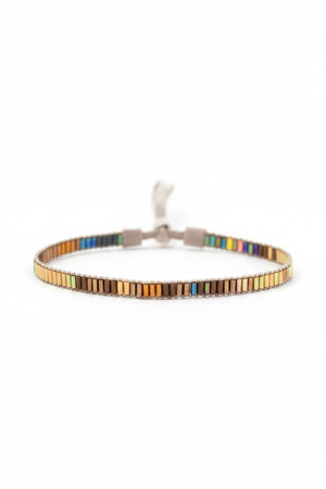 The JULIE ROFMAN - MINI BRACELET by JULIE ROFMAN JEWELRY is a vibrant handwoven piece adorned with small, square beads in various shades of pink, red, and white. It is displayed against a white background and includes a straightforward sterling silver clasp for convenient fastening.