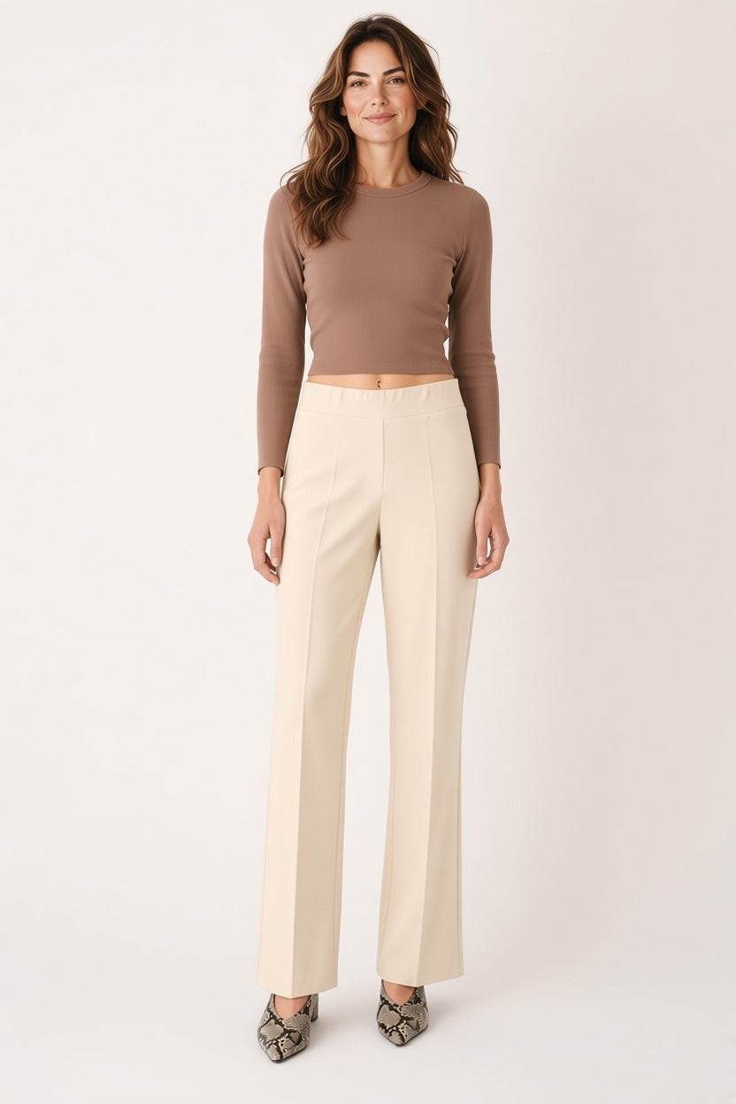Back view of a person wearing a mauve, short-sleeved top and MEIMEIJ - PULL ON PANT IN SUGAR SWIZZLE, which are cream-colored, flared-leg trousers designed for tailored comfort.