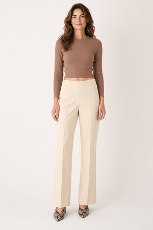 Back view of a person wearing a mauve, short-sleeved top and MEIMEIJ - PULL ON PANT IN SUGAR SWIZZLE, which are cream-colored, flared-leg trousers designed for tailored comfort.