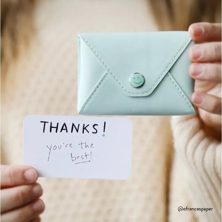 The E. FRANCES PAPER E. FRANNIE PACK, SEAGLASS is a mint green wallet with a snap closure, embossed with "E. FRANCES," ideal for holding Little Notes—perfect as a gift and shown against a white background.