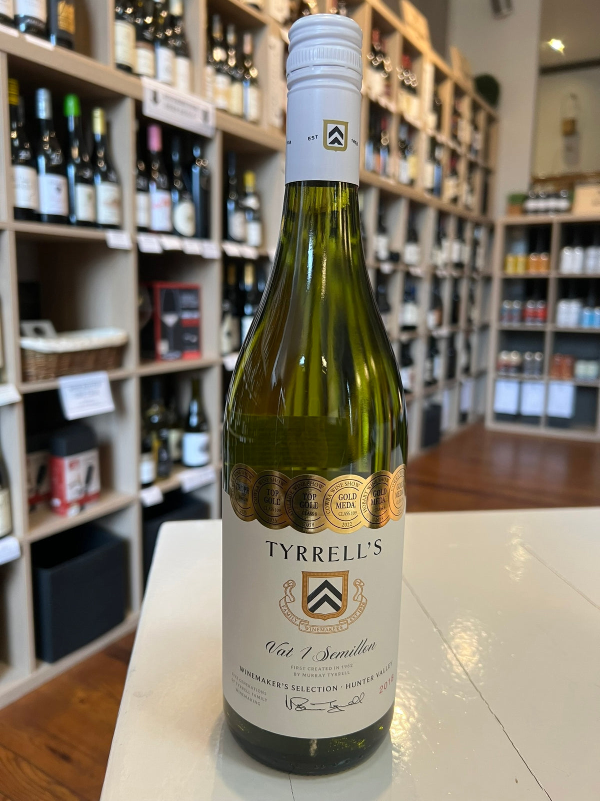 A bottle of TYRRELL'S VAT 1 SEMILLION 2018 by WINEBOW, featuring a white and gold label with multiple award medallions at the top and a white screw cap.