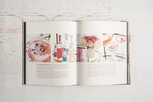 A close-up of THE ART OF THE BAR CART BY VANESSA DINA from CHRONICLE BOOKS, featuring a gold-patterned spine and an illustrated bar cart on the cover—ideal for drink ideas and elegant home bar decor.