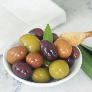 A glass jar of DIVINA - GREEK OLIVE MIX, featuring a green label and filled with assorted, traditionally cured Greek olives, set against a white background.