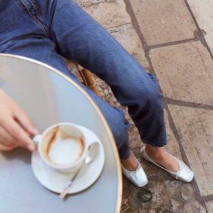 Top view of the REQINS - HARMONY BALLERINA FLATS IN METALIC SILVER by REQINS, featuring shimmering silver leather and a front bow, captured on a plain light background for a chic metallic look.