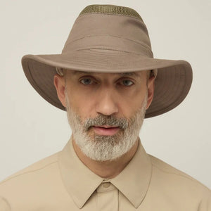 A man with a gray beard and mustache wears the TILLEY Airflo Hikers Hat T4MO-1 in olive, featuring UPF 50+ sun protection, and a beige button-up shirt, looking directly at the camera against a plain light background.