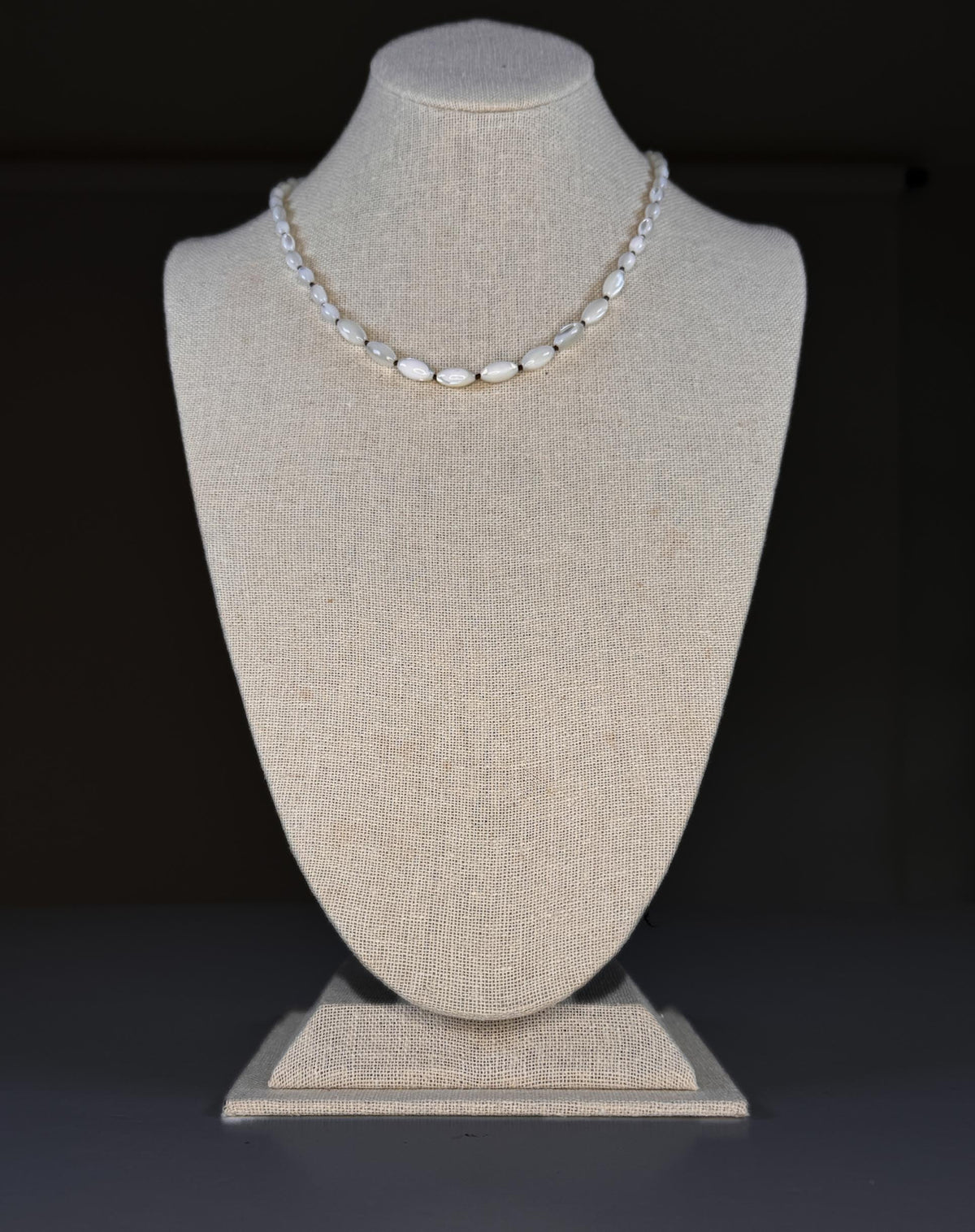 The SANDRINE FRANCE STUDIO - GIANNA NECKLACE features handmade oval white beads, reminiscent of hand-knotted shells, separated by small gold spacers and displayed in a loose curve on a plain white background.