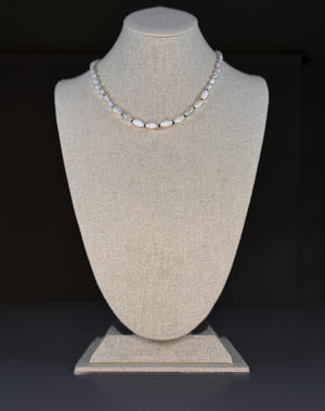 The SANDRINE FRANCE STUDIO - GIANNA NECKLACE features handmade oval white beads, reminiscent of hand-knotted shells, separated by small gold spacers and displayed in a loose curve on a plain white background.