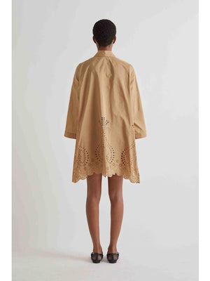 A person stands against a white background wearing the MEIMEIJ Lasercut Cotton Shirt Dress featuring eyelet embroidery and scalloped cuff hems, paired with black flat shoes.