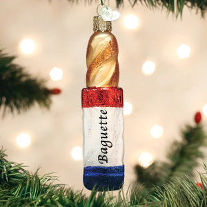 Old World Christmas BAGUETTE ORNAMENT shaped like a French bread baguette, featuring a gold spiral top and a red, white, and blue base labeled with the word “Baguette.”