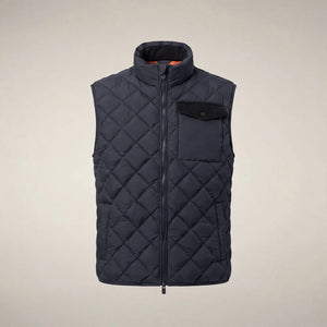 A person stands facing forward, wearing the SAVE THE DUCK - FABRICE Puffer Vest in Blue Black from SAVE THE DUCK, featuring recycled Plumtech insulation, layered over a black long-sleeve shirt and gray pants. They have a neutral facial expression and are posed against a plain white background.