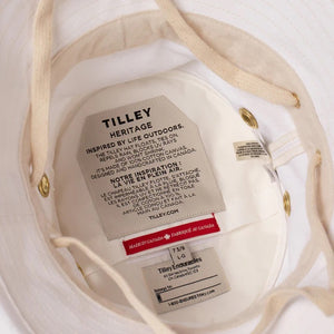 A person wearing the TILLEY - ICONIC T1 BUCKET HAT IN WHITE and a white shirt is shown from the back against a light gray background—a stylish, breathable cotton hat by TILLEY, perfect for sun protection.