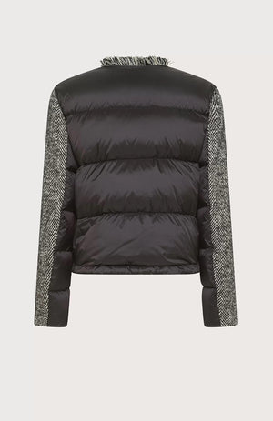 A woman stands confidently against a gradient background, wearing the SEVENTY - Wool Blend Jacket with Puffer Back by SEVENTY. She pairs the grey jacket with high collar with black tailored pants featuring a front slit and completes her outfit with black high-heeled shoes. Her long, dark hair is styled in loose waves as she looks directly at the camera.