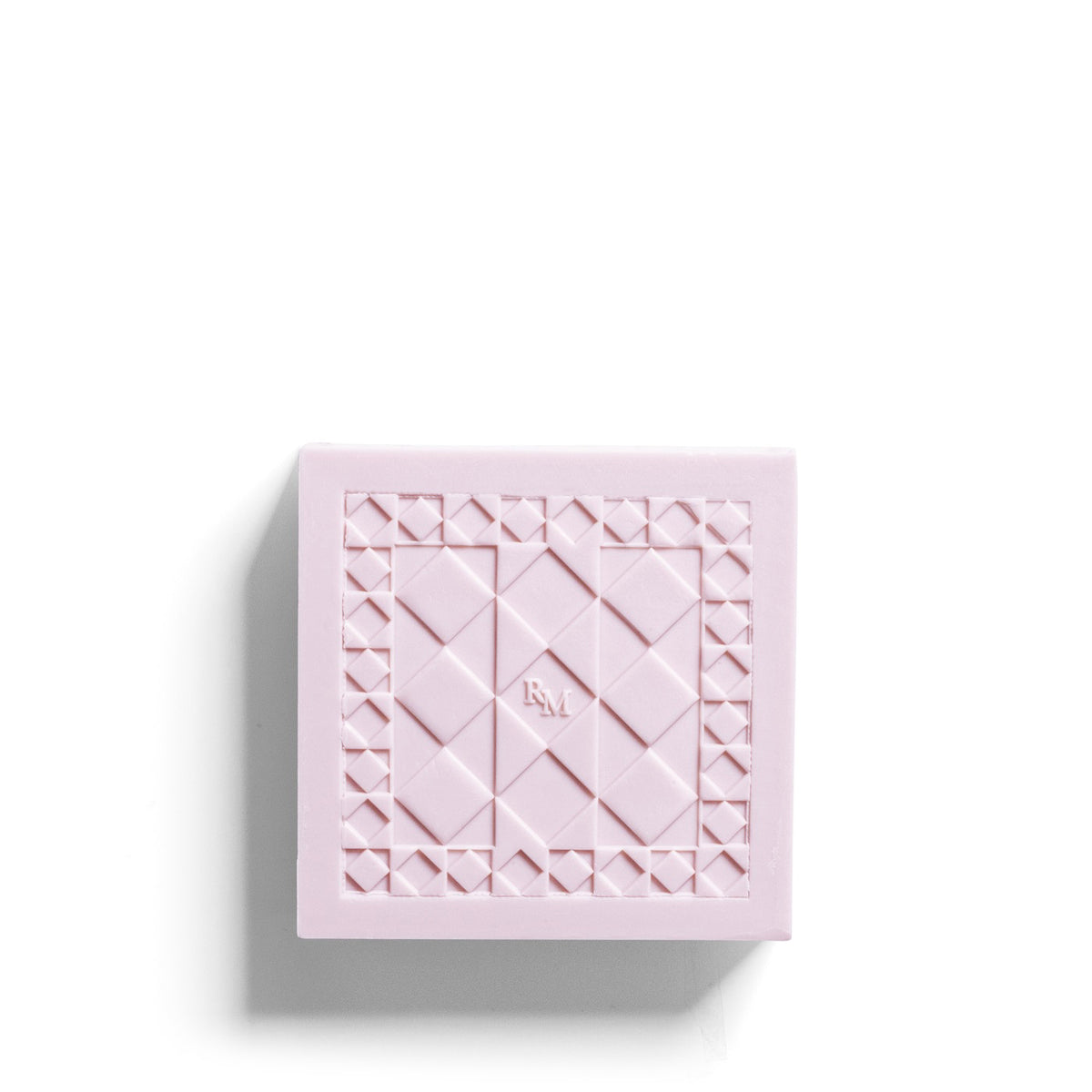 The ROSE ET MARIUS &quot;A Siesta in a Sunlit Home&quot; scented soap, with its geometric honeycomb pattern and elegant pink-and-white packaging, slides from a matching box reminiscent of artisan-crafted perfumed soaps.