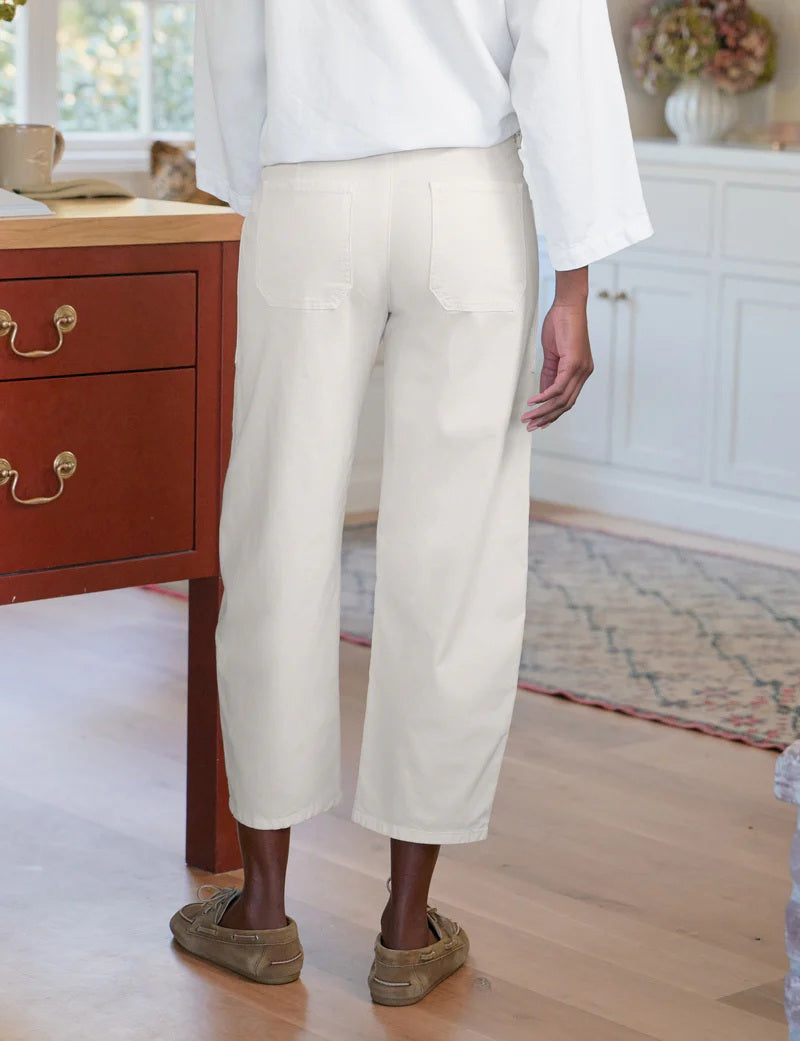 A person wearing FRANK &amp; EILEEN’s Bray Everyday Barrel Pant in Italian Peached Twill Chalk pairs them with a white long-sleeve top, standing casually with one hand in their pocket.