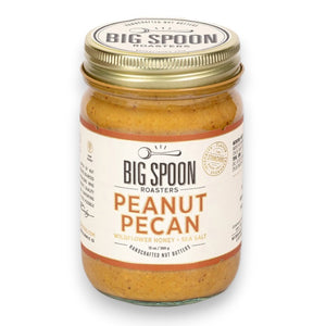 A jar of BIG SPOON ROASTERS Pecan Peanut Wildflower Honey Nut Butter with a gold lid. The label shows it contains wildflower honey, organic coconut oil, and sea salt. The jar is 13 oz or 369 g and is described as handcrafted nut butter from BIG SPOON ROASTERS.