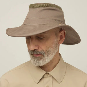 A man with a gray beard and mustache wears the TILLEY Airflo Hikers Hat T4MO-1 in olive, featuring UPF 50+ sun protection, and a beige button-up shirt, looking directly at the camera against a plain light background.