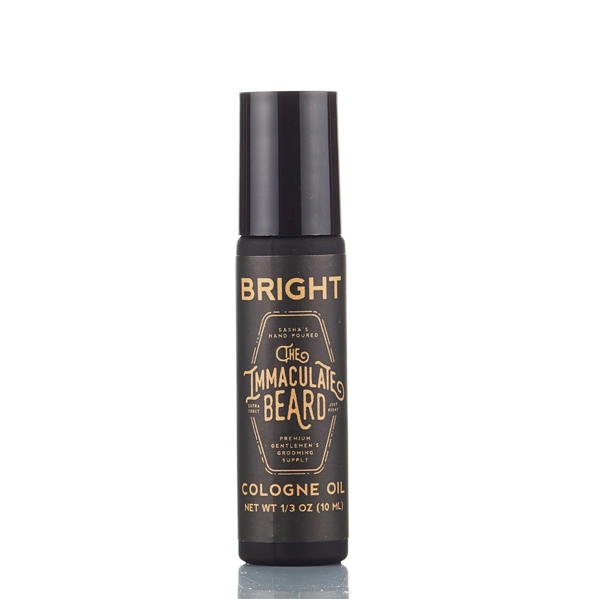 A black cylindrical bottle labeled "THE IMMACULATE BEARD - COLOGNE OIL IN FIRST LIGHT" with gold text and a sandalwood vanilla scent contains 1/3 oz (10 mL) and stands upright against a white background.
