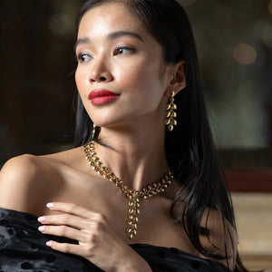 The CAPUCINE DE WULF Laurel Dangle Earrings feature textured leaf-shaped drops with a cluster of round beads on top, crafted from 18K gold over brass and shown against a white background.