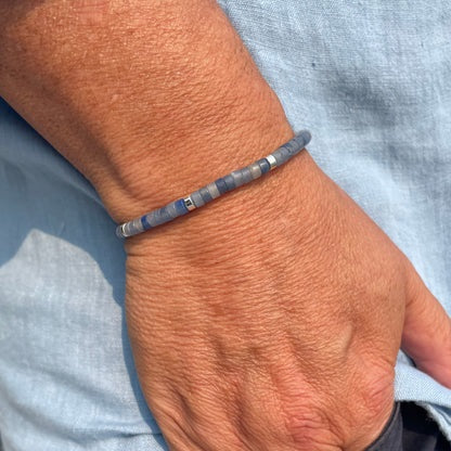 The STOLEN RICHES Ibiza Bracelet in Aventurine Heishi Stone features minimalist flat green beads with metallic accents on an adjustable dark cord, adding a perfect bohemian touch to your style.