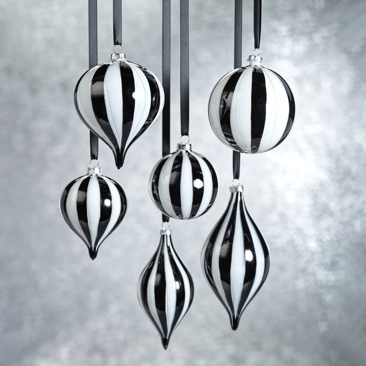 ZODAX TWILIGHT STRIPE GLASS ORNAMENT: a 4-inch diameter glass ornament featuring alternating black and white vertical stripes, hanging from a grey ribbon.
