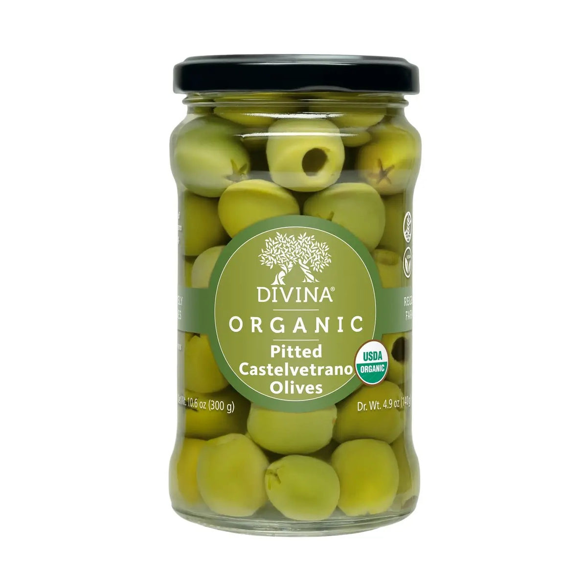 A glass of clear liquid with three DIVINA - ORGANIC PITTED CASTELVETRANO OLIVES on a skewer rests on top. Nearby, a bowl of DIVINA olives, a knife, and part of a wooden board are visible.