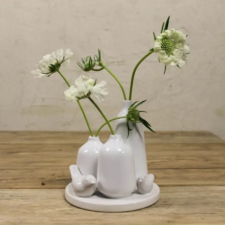 The HOMART CERAMIC VASE TRIO WITH TWO BIRDS features three matte white minimalist vases of varying heights and two bird figurines on a 5.5-inch round base; tallest vase stands 5 inches—ideal for bird vase decor.