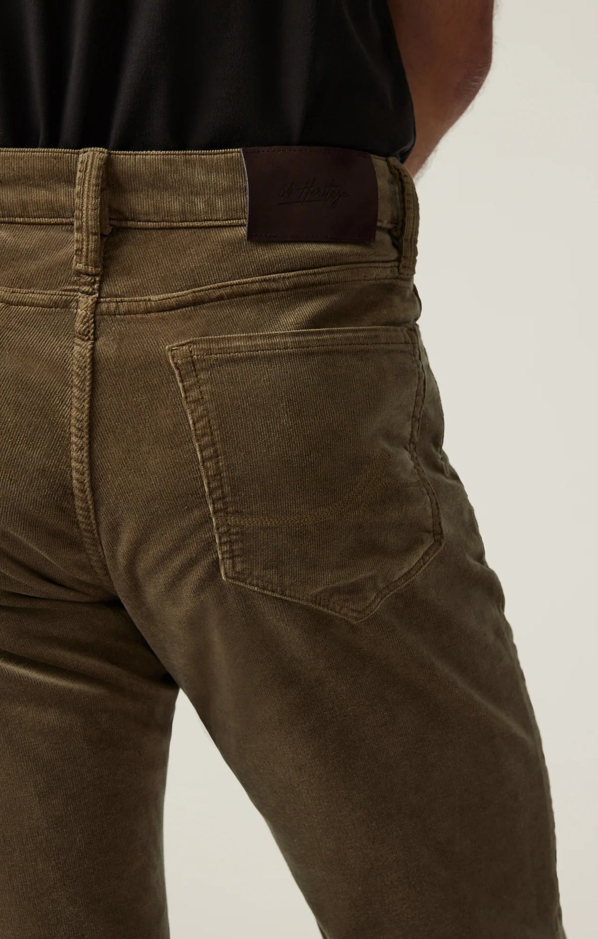 Man wearing 34 HERITAGE - COURAGE STRAIGHT LEG CORDUROY PANTS IN TOBACCO and white sneakers.