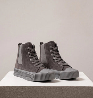 The DANIELLA LEHAVI - OSAKA HIGH TOP SNEAKER by DANIELLA LEHAVI features gray suede uppers and ribbed rubber soles, shown on a white pedestal against a plain light background. These stylish high-tops perfectly combine everyday comfort with modern style.
