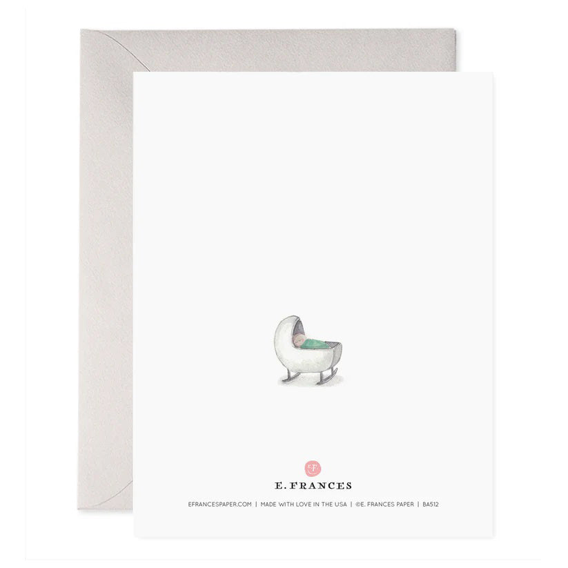 The E. FRANCES PAPER - NEW MAMAS ROCK GREETING CARD features a handcrafted watercolor of a rocking chair with a light green cushion, alongside the words "New mamas rock and rock and rock and love and love and love." An envelope is slightly visible behind the card.