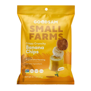 A yellow bag of GOODSAM FOODS GOODSAM - BANANA CHIPS stands upright on a light surface beside a bowl of banana chips, with a “NEW” label in the top left highlighting women-led innovation for healthy snacks.