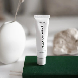 A white tube labeled "JAXON LANE - RELAX AND REPAIR ANTI AGING FACE MOISTURIZER" stands beside a matching black box. This fragrance-free men's moisturizer from JAXON LANE contains 2.03 fl. oz. (60 ml) of product.