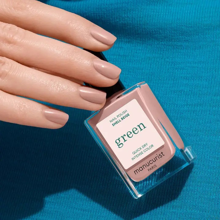 A bottle of MANUCURIST INC’s GREEN™ Nail Polish in Shell Beige, presented in a square glass bottle with a black cap and a white label displaying green and beige text. This non-toxic pinky beige polish combines elegant color with a clean, vegan formula.