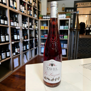 A bottle of LES LAUZERAIES TAVEL ROSÉ 2025 from WINE: MONSIEUR TOUTON, featuring a pink label reading “Tavel” and a silver foil top, set against a plain white background. This distinguished Rhône Valley wine is celebrated for its dark-style rosé character and vibrant color.