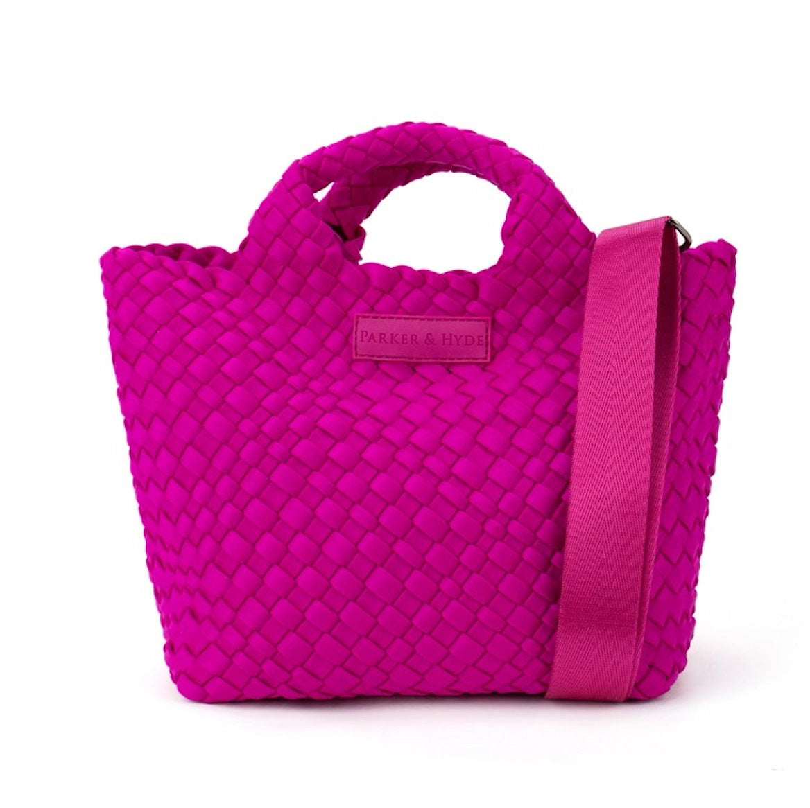 A woman with long brown hair, in a sleeveless cream knit top and blue jeans, holds a PARKER AND HYDE - MINI WOVEN TOTE BAG. The hand-woven tote by PARKER &amp; HYDE features a subtle checkered pattern with light blue accents.