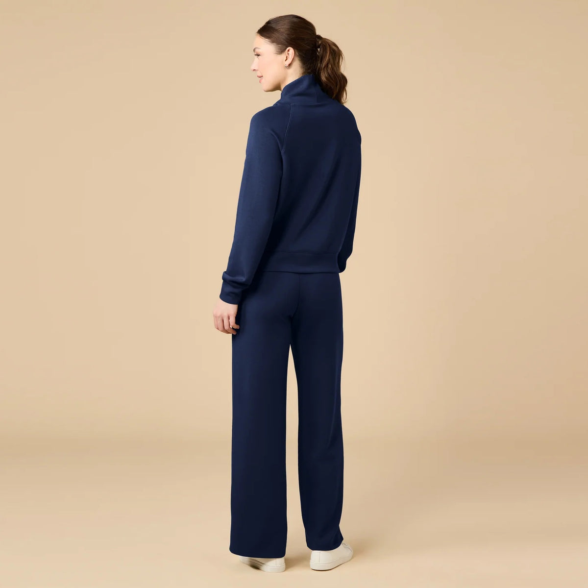 A woman seen from behind wearing the fuchsia SOFTIES - DREAMTECH COWL NECK WITH PLEATED PANT set featuring a long-sleeved cowl neck top and matching pleated pants.