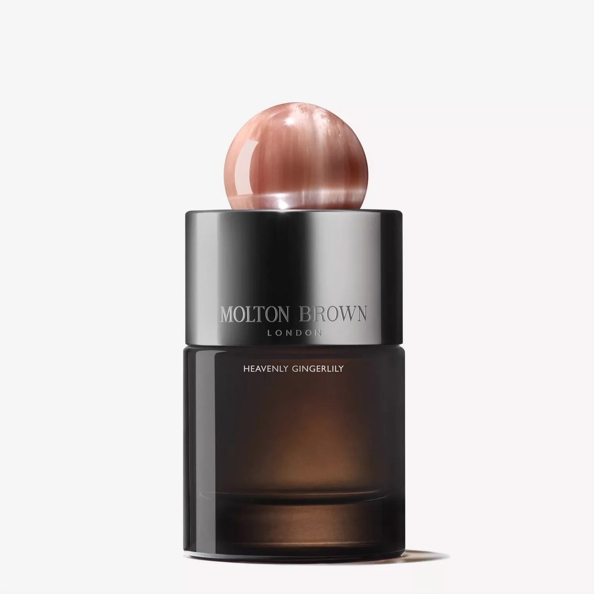 A bottle of MOLTON BROWN - GINGERLILY EAU DE PARFUM, with a dark translucent base, metallic branded band, and shiny round pinkish cap, is displayed against a white background.