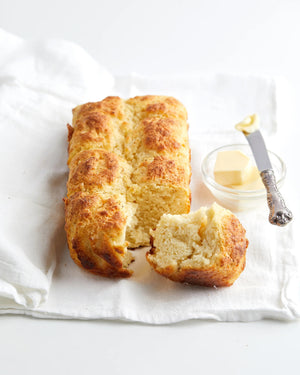 A white package of MAISON ZOE FORD - FLUFFY BUTTERMILK BREAD mix is shown. The front features an image of buttery buttermilk bread on a white plate with an open jar of honey and a honey dipper. The 608-gram package makes 8 fresh dinner rolls.